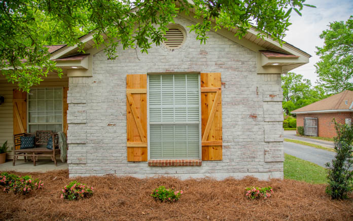 Brick home with cedar shutters and beautifully landscaped flower beds