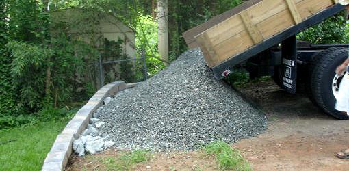Dump truck dumping gravel in a yard