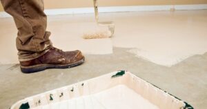 man painting over concrete floor