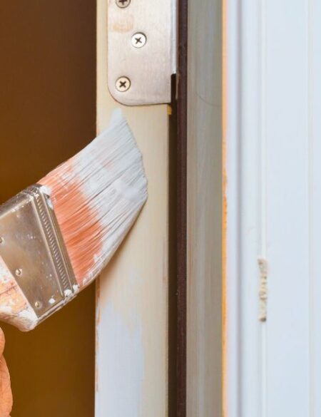 person painting a door hinge