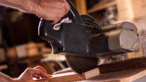 Man cutting wood with miter saw sawdust flying everywhere
