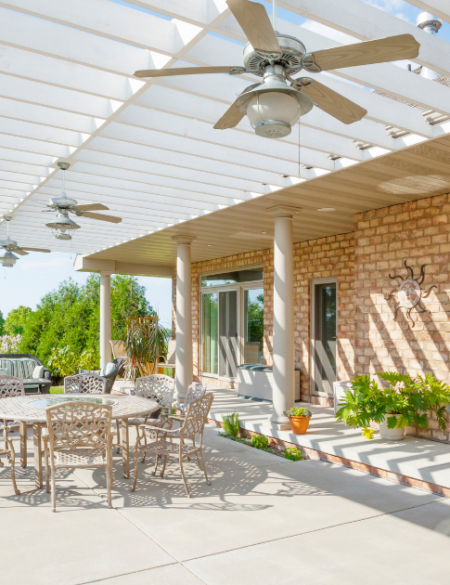 Photo of a concrete patio with patio furniture on it and an awning with a ceiling fan.