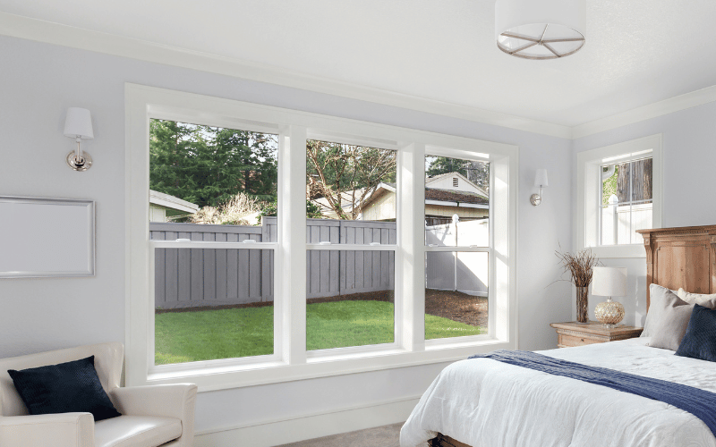 Bedroom with double-hung windows showing a backyard view