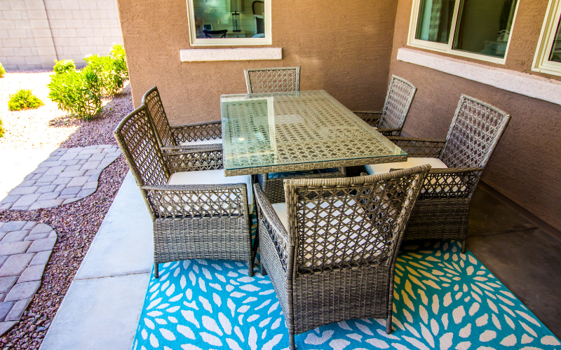 Photo of a concrete patio covered by a blue and white rug. 
