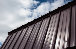 Slanted brown tin roof in front of a cloudy sky backdrop